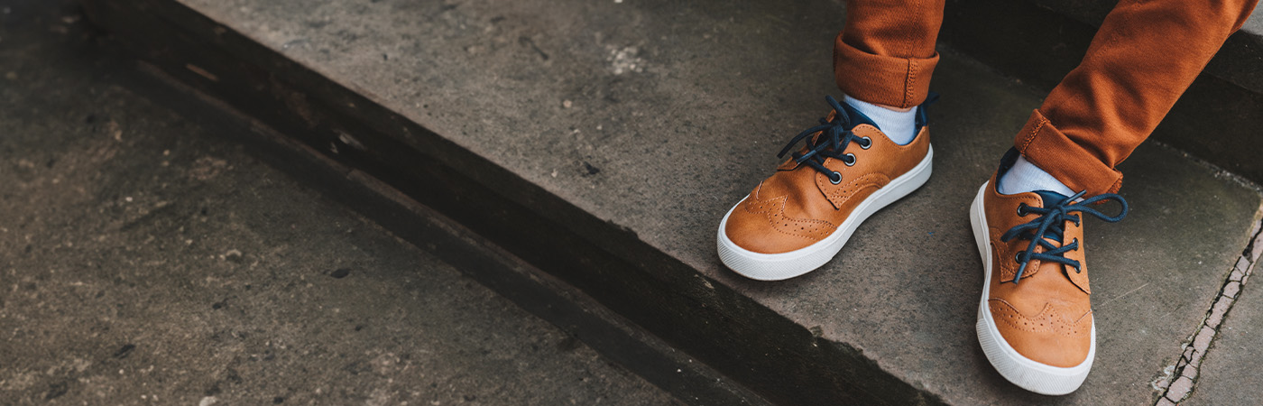 נעלי סניקרס חומות לגברים על רקע מדרגות בטון באווירה אורבנית