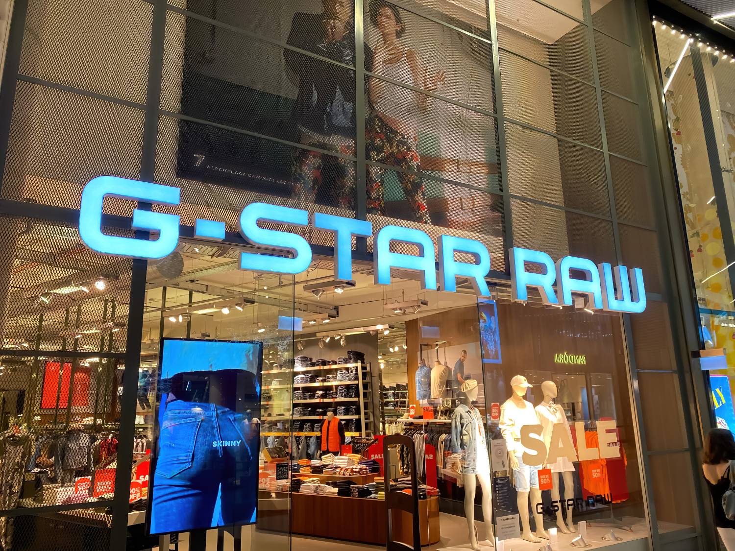 חזית חנות G-Star Raw עם לוגו בולט ותצוגת בגדים. מבט על הכניסה לחנות בקניון בגרמניה.